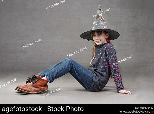 Little girl in jeans witch hat and funny boots. Child at the halloween party