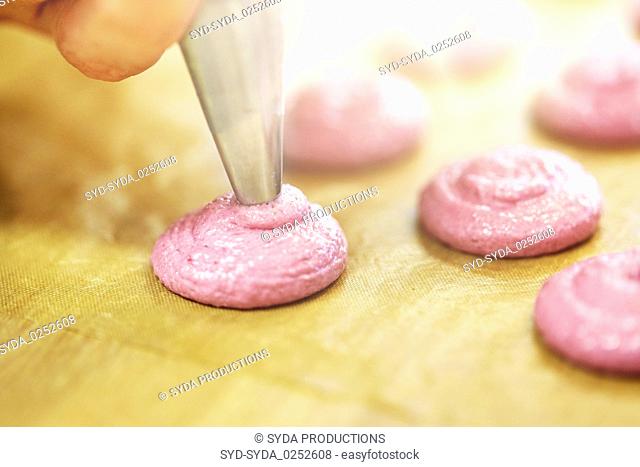 chef with nozzle squeezing macaron batter