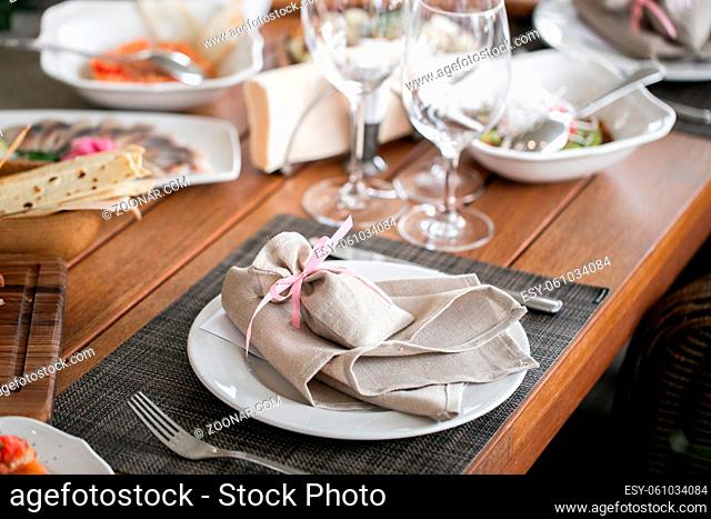 Decorated table, a plate of neatly arranged napkin, fork and knife. Beautifully decorated table with white plates, crystal glasses, linen napkin