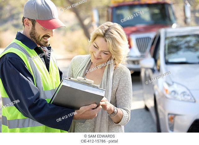 Roadside mechanic and woman reviewing paperwork