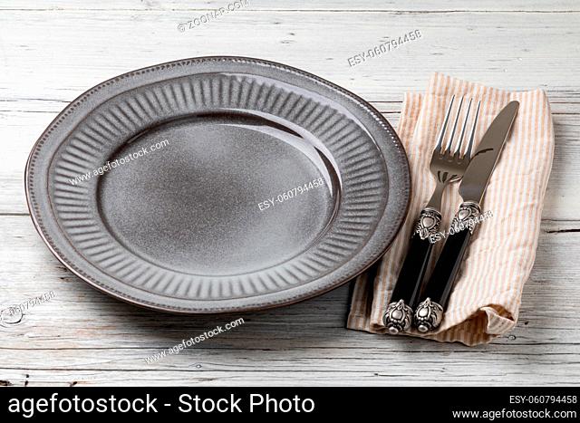 Table setting. plate, knife and fork on a wooden table