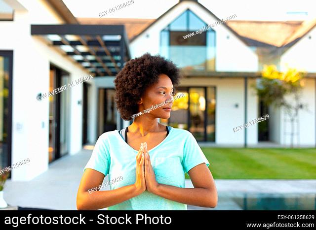 Afro young african american woman with hands clasped practicing yoga in backyard