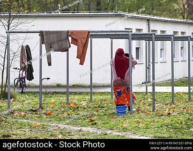 14 November 2023, Brandenburg, Zossen: A woman hangs up laundry in the initial reception center of the Central Foreigners' Registration Office (ZABH) in the...