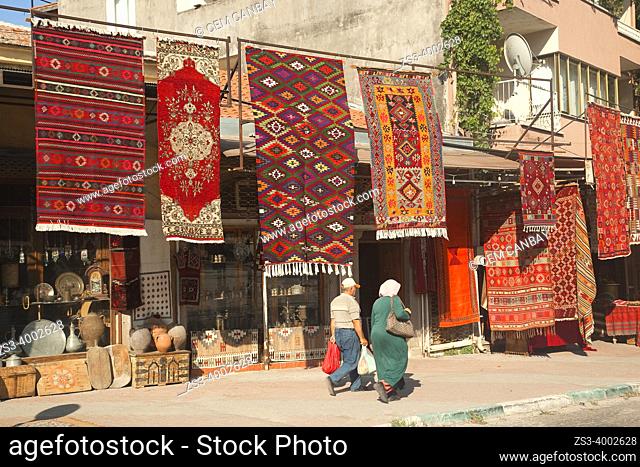 Couple in front of the traditional shops selling carpets and rugs at the old town of Bergama, Izmir, Aegean Region, Turkey, Europe