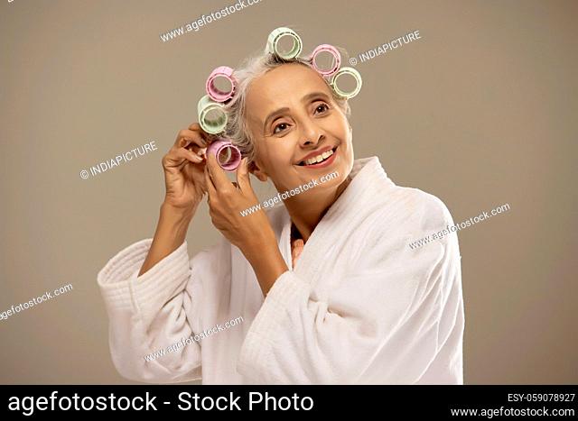 An old woman opening the rollers on her hair