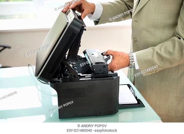 Close-up Of Businessman Fixing Cartridge In Photocopy Machine In Office