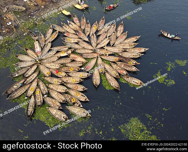 DHAKA, BANGLADESH - APR 20, 2022: Aerial view of Hundreds of wooden boats grouped fan out which look like the petals of a flower for a busy morning commute on...