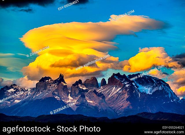 The black-and-steel color of the cliffs of Los Cuernos. Magnificent orange clouds in the rays of the sunset. The concept of extreme and active tourism