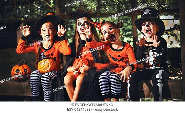 happy Halloween! a group of children in suits and with pumpkins in the forest