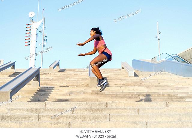 Young woman during workout on stairs, jumping