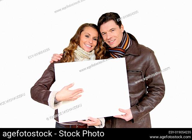 Smiling couple holding white message board