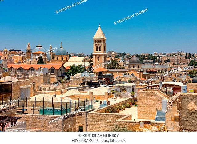 Domes and belfries among typical stone buildings and rooftops under blue sky in Old City of Jerusalem, Israel