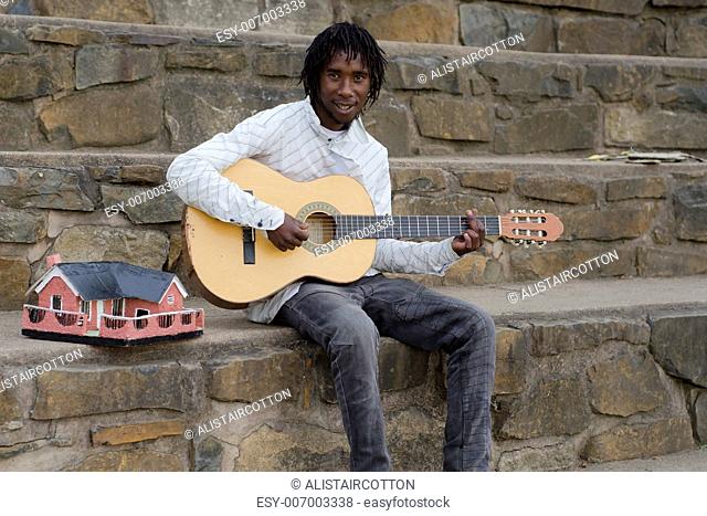 African busker in Howick, KwaZulu-Natal with ethnic model house collecting money