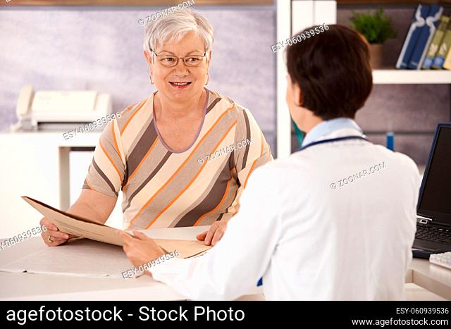 Female pensioner at doctors office listening to doctors explanation