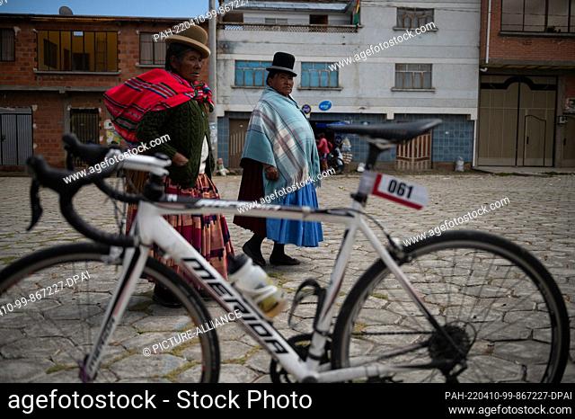 09 April 2022, Bolivia, Jankho Amaya: Two older women take a closer look at the bicycle of a race participant. The ""Poncho rojo"" (red poncho) race attracts...