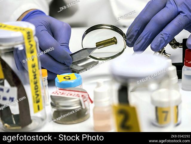Expert police examines a bullet cap in scientific laboratory with magnifying glass