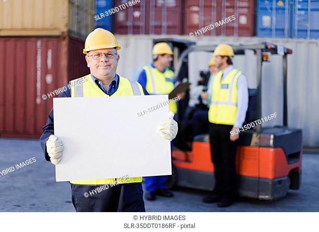 Worker holding sheet in shipping yard