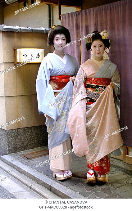 PORTRAIT OF A GEIKO GEISHA, ON THE LEFT, AND A MAIKO APPRENTICE WEARING A KIMONO OBEBE HELD CLOSED BY A WIDE BELT OBI AND WOODEN SANDALS OKOBO