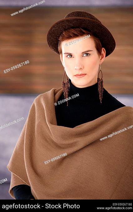 Trendy young woman wearing hat, big scarf and earring