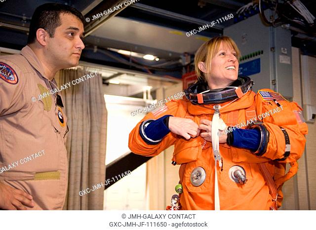 Astronaut Kathryn Hire, STS-130 mission specialist, dons a training version of her shuttle launch and entry suit in preparation for a training session in the...