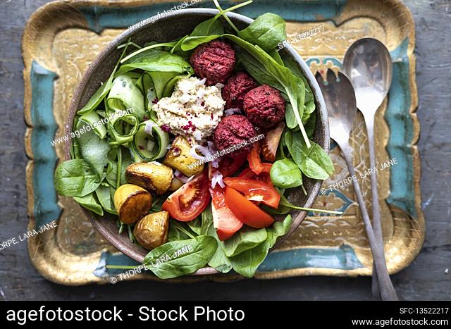 Cucumber and spinach salad with beetroot falafel, hummus and roast potatoes