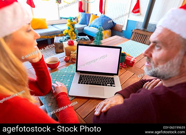 Happy caucasian mature couple making a video call and using laptop with copy space