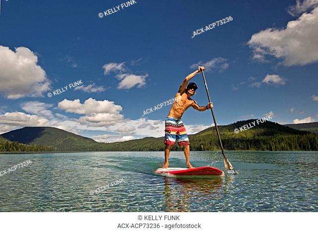 A paddle boarder makes his way across the stunning waters of Johnson Lake, North of Kamloops in the Thompson Okanagan region of British Columbia, Canada