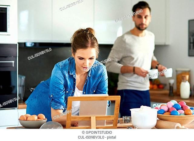 Couple drinking coffee and using digital tablet in kitchen