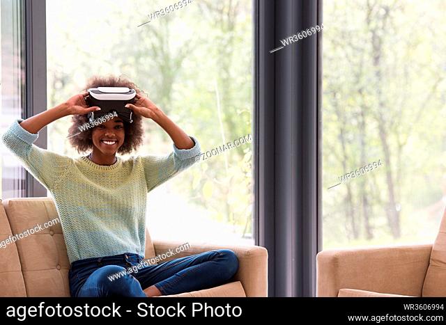 Happy african american girl getting experience using VR headset glasses of virtual reality at home