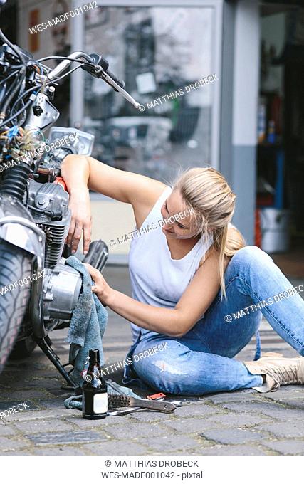 Young woman cleaning motorbike
