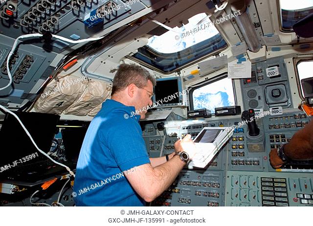 Astronaut Steve Frick, STS-122 commander, looks over a checklist while working on the aft flight deck of Space Shuttle Atlantis during flight day two activities