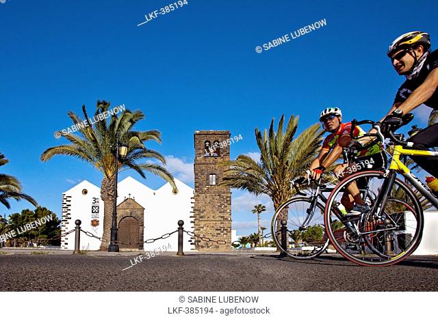 Cyclist passes the Church Iglesia Nuestra Senora de Candelaria, La Olvia, Fuerteventura, Canary Islands, Spain