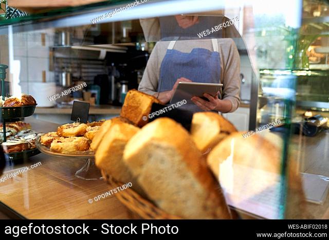 Baked pastry food in display with coffee shop owner using tablet PC