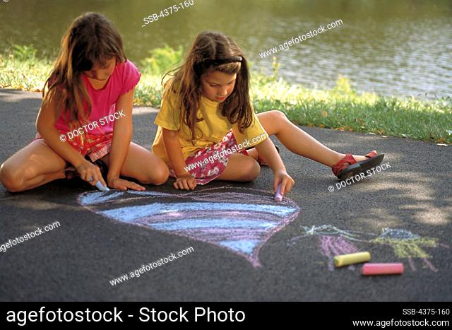 Young Sisters Draw with Sidewalk Chalk