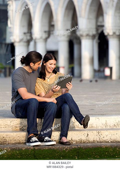 Italy, Venice, Young couple using digital tablet on St. Mark's Square