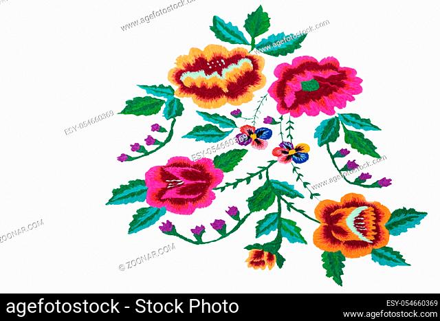 Crafts: beautiful colorful flowers and green leaves embroidered with satin stitch on white background. Manual work