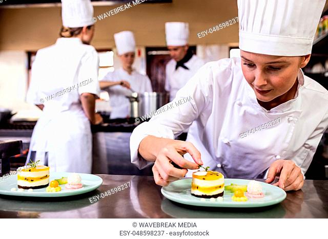 Female chef garnishing delicious desserts in a plate