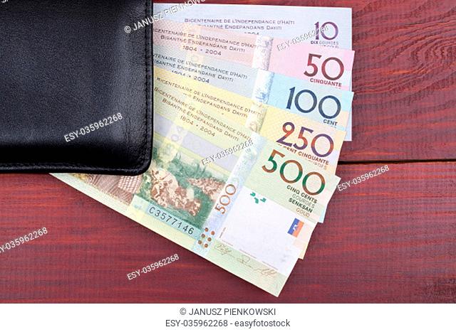 Black wallet with Haitian money on a wooden background