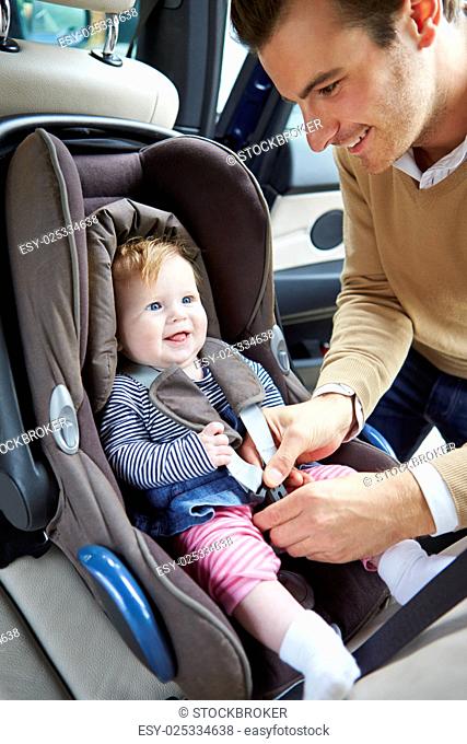 Father Putting Baby Into Car Seat