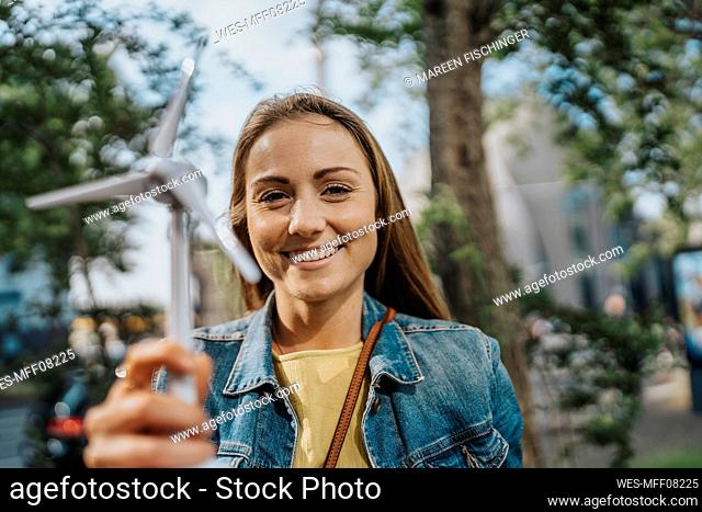 Smiling young woman holding wind turbine model