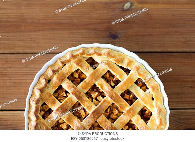 close up of apple pie in mold on wooden table