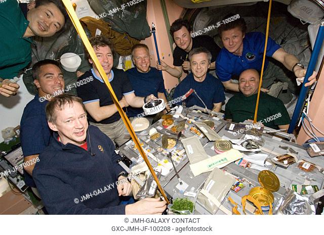 Nine of a total aggregation of 13 astronauts and cosmonauts are pictured at meal time aboard the International Space Station