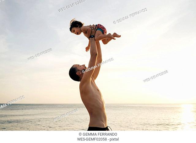 Thailand, Koh Lanta, father playing with his little daughter on the beach at sunset