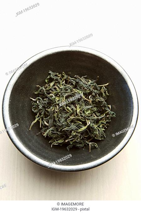Dried tea leaves on ceramic plate, overhead view