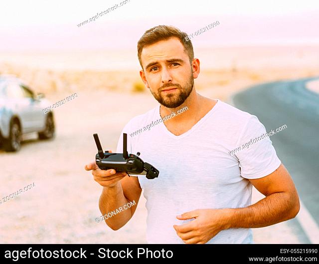 Guy controls drone with remote control, desert