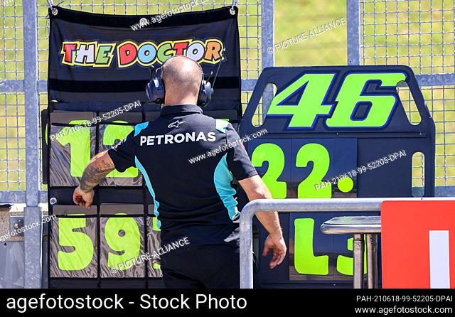18 June 2021, Saxony, Hohenstein-Ernstthal: Motorsport/Motorcycle, German Grand Prix, MotoGP at the Sachsenring: A member of the race team puts up the notice...