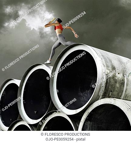 Relay runner with baton going over large cylinders