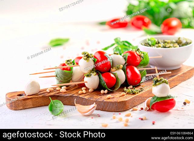 Caprese salad-mozzarella, basil, cherry tomatoes, pesto sauce, skewers. Italian homemade food and a healthy diet concept