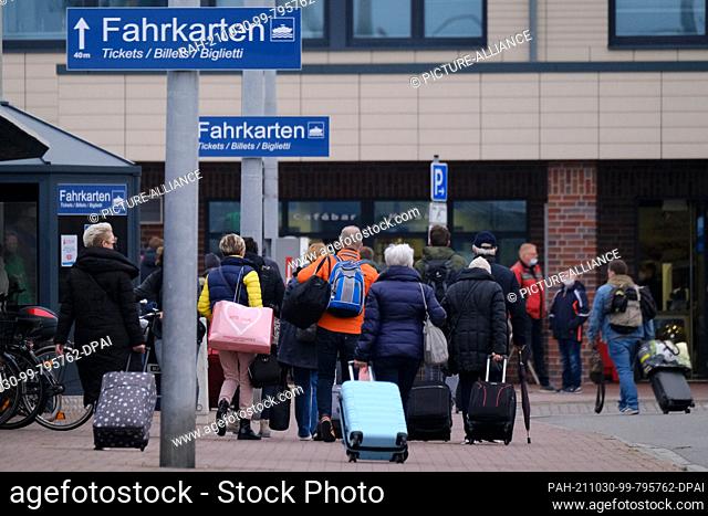 30 October 2021, Lower Saxony, Norddeich: People walk with their luggage to Norddeich Mole station on Saturday morning. The autumn holidays in Lower Saxony are...