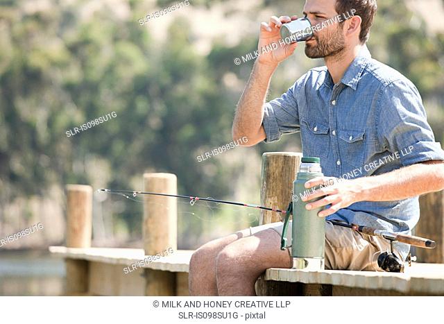Man with fishing rod and hot drink